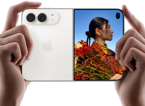iPhone Duo, kleur Sterrenwit, met twee handen vastgehouden in liggende stand, opengevouwen, linkerkant met 48-MP Dual Fusion-camera’s aan de achterkant, op het buitendisplay rechts staat iemand die wordt gefotografeerd en dankzij Duo Preview tegelijkertijd zichzelf kan zien