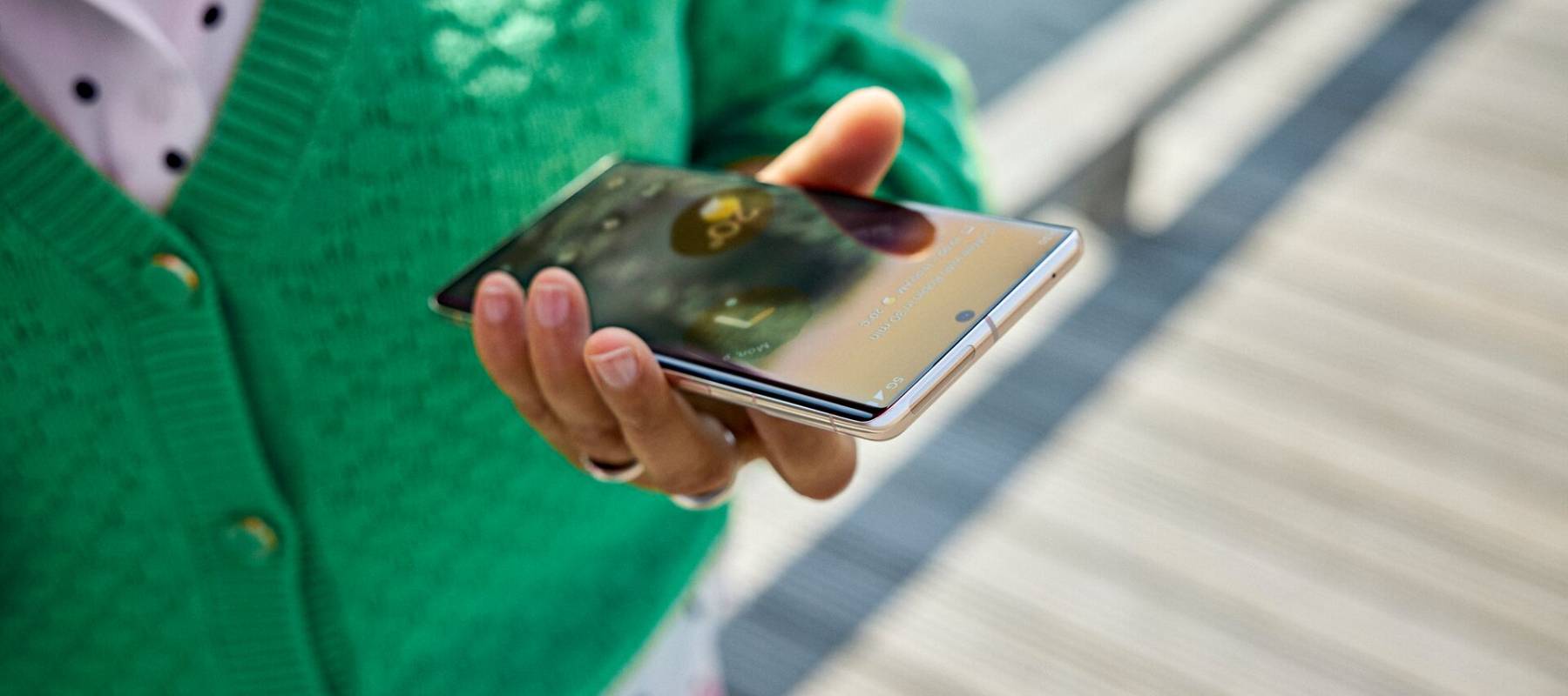 Persoon met groen vest houdt telefoon in de hand