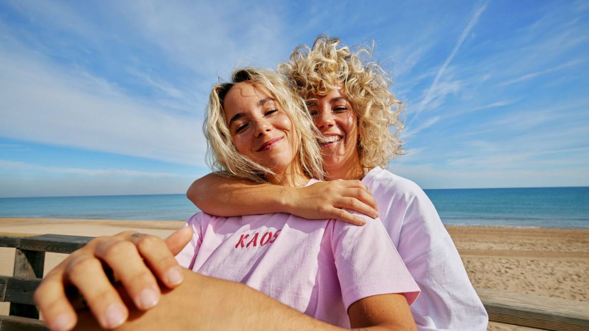 Twee jonge vrouwen op het strand met zee op de achtergrond