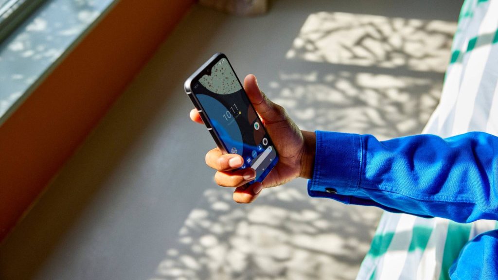 Persoon met blauwe kleding houdt telefoon in de lucht
